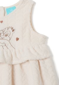 Cremfarbendes, ärmelloses Kleid aus weicher Fleeceware, mit besticktem Design und ausgestelltem, Rüschensaum mit Herzmotiven.