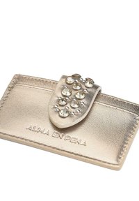 Tarjetero de cuero metálico dorado con un acabado texturizado, que presenta una solapa decorativa adornada con gemas transparentes y acentos de hardware plateado.