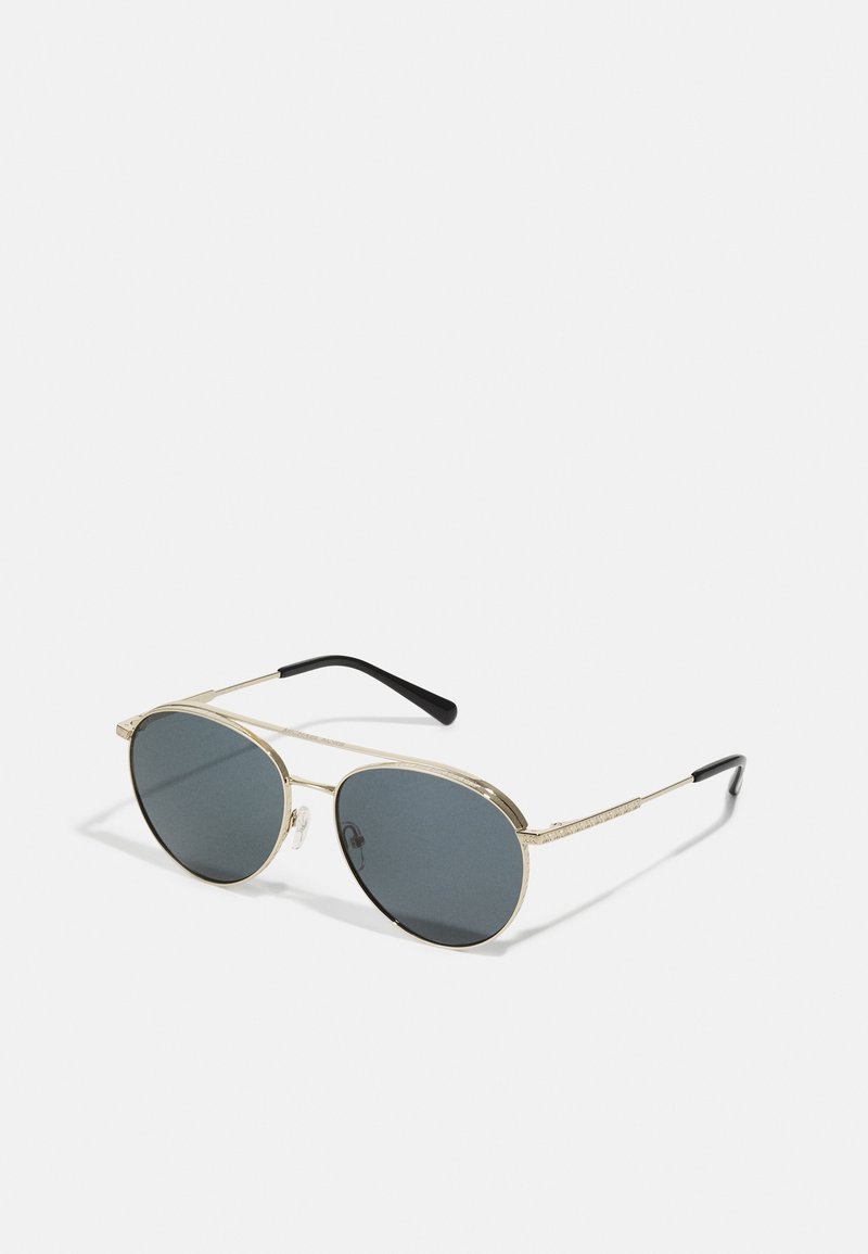 Lunettes de soleil aviateur en métal doré avec des verres gris foncé. Présentent des détails texturés sur la monture et des embouts en acétate noir sur les branches.