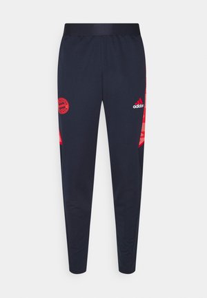Granatowe spodnie dresowe Adidas z czerwonym logo Bayernu Monachium na lewej udzie i czerwonym logo Adidas na prawej udzie, zwężane nogawki oraz elastyczny pas.
