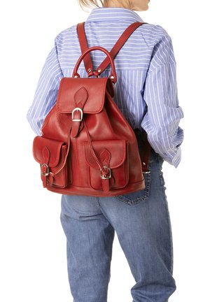 Zaino in pelle rossa con spallacci regolabili, chiusura a patta superiore e due tasche frontali con dettagli in fibbia. Texture liscia, forma cilindrica.