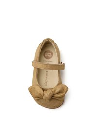 Zapato de bailarina de ante color tostado con una correa ancha, que presenta un gran lazo en la puntera. El interior incluye un logo y el texto "¡un buen día!".