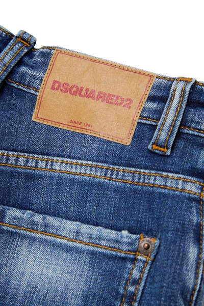 Jeans di denim con un'etichetta in pelle marrone con "DSQUARED2" impresso in rosa, cuciture a contrasto e un lavaggio blu sbiadito con dettagli d'usura.