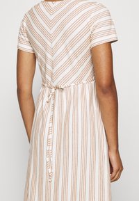 Abito a maniche corte con una fantasia a righe verticali beige e bianche, caratterizzato da un collo a V e un nastro in vita. Tessuto morbido, design casual.