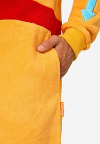 Yellow fleece garment with red stripes, featuring a pocket and blue arrow detail on the sleeve. Tag displays "OPPOSUITS." Soft texture.