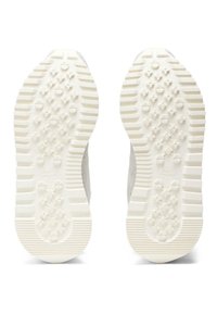 Die Schuhsohlen bestehen aus strukturiertem weißen Gummi mit einem Muster aus kleinen Punkten und Rillen für besseren Halt. Die Markenkennzeichnung ist in der Mitte sichtbar.