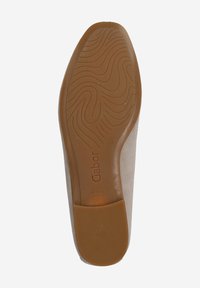 Semelle en caoutchouc marron d'une chaussure avec un motif de semelle ondulée et une marque. La tige est en daim beige avec une texture lisse. Fabriqué au Portugal.