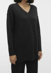 Maglione nero oversize realizzato in materiale morbido, con scollatura a V, maniche lunghe e polsini e orlo a coste. Design semplice e minimalista.