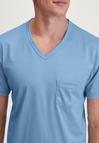 Lichtblauw V-hals T-shirt van zacht katoen, met korte mouwen en een klein borstzakje met een effen textuur.