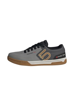 Gray and black sneaker with a rubber sole. Features textured upper, prominent logo in gold, and black laces. Designed for versatility and performance.