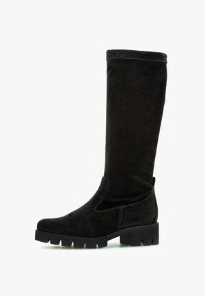 Black knee-high boots made of soft suede, featuring a block heel and smooth stitching details. The sole has a textured grip pattern.