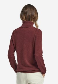 Burgunderfarbener Rollkragenpullover mit gerippten Bündchen und Saum, aus weichem Material gefertigt, mit taillierter Schnittführung und nahtlosem Rücken.