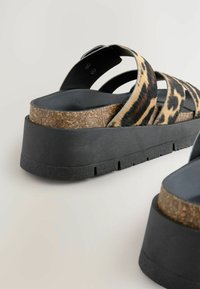 Zwarte platform sandalen met leeuwenprint banden, kurken voetbed en gestructureerde rubberen zool. Beschikt over twee brede kruisbande en een verstelbare gesp.