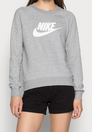 Šedá mikina s kulatým výstřihem, dlouhými rukávy a raglánovým designem. Na přední straně se nachází velké bílé logo Nike. Kombinujte s černými šortkami.