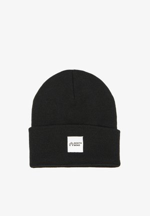 Jachetă puffer bleumarin cu un căptușeală texturată neagră și butoane metalice, asociată cu o căciulă tricotată neagră cu un patch alb.