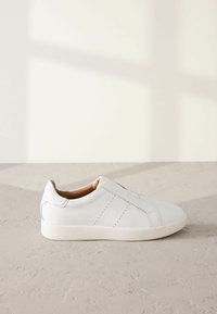 Hvide lædersneakers med en glat overflade, der har syede detaljer og et slip-on design. Letvægtsgummisål for komfort.