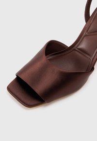 Brun sateng slingback hæl med en bred tårem, firkantet tåform og en teksturert såle, med et elegant og minimalistisk design.