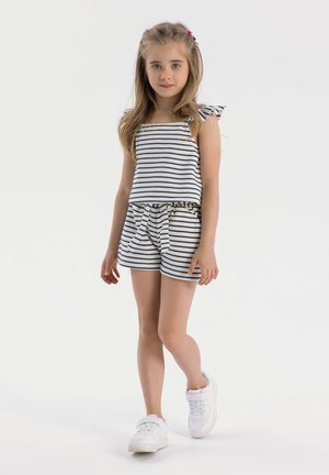 Gestreepte tanktop en shorts set in marineblauw en wit, met een rimpeldetail op de schouder en een vastgebonden taille. Gecombineerd met witte sneakers.