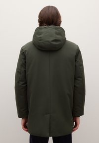 Parka verde scuro con texture imbottita, grande cappuccio e taglio dritto. Presenta un design minimalista senza elementi metallici o decorazioni visibili.