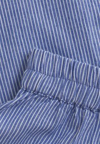 Blå och vit randig tyg med en mjuk textur. Har ett rynkat midjeband med sömdetaljer och jämna ränder genom hela tyget.