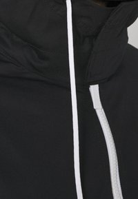 Black jacket featuring a high collar, white zipper, and white drawstring. Material appears smooth with minimal stitching details.