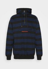Felpa nera con righe orizzontali blu, dotata di tasca con cerniera frontale e logo "Cleptomanicx" rosso sul petto. Materiale in cotone, design casual.