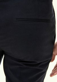 Mörkblå byxor i slät tyg, med en enda bakficka med en diskret sömdetalj. Slim fit med en ren design.