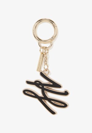 Gold metal keychain featuring a black signature design attached to a round ring, includes a small tag with branding detail.
