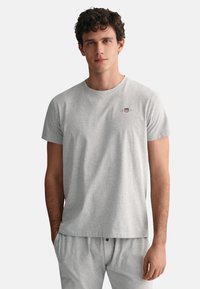 Gray cotton t-shirt featuring a crew neck, short sleeves, and a small embroidered logo on the chest. Smooth texture and relaxed fit.