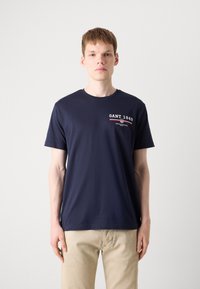 Navyblauwe katoenen t-shirt met korte mouwen en ronde hals, voorzien van het logo "GANT 1949" in het wit en rood op de linkerborst.