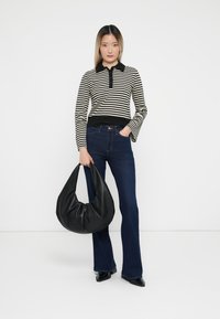 Gestreifter Langarm-Poloshirt in Schwarz und Weiß, dunkelblaue Schlagjeans und eine große schwarze Leder-Hobo-Bag. Glattes Material, taillierte Silhouette.