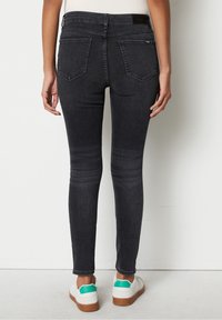 Tummanharmaat kapeat farkut, joissa on keskikorkea vyötärö, takataskut ja hienovarainen kulutus. Yhdistetty valkoisiin tennareihin, joissa on vihreitä yksityiskohtia.