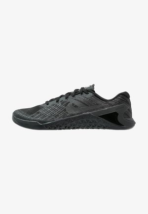Chaussure de sport noire et grise avec semelle texturée, empeigne en mesh, lacets et profil bas conçue pour l'entraînement ou la course.