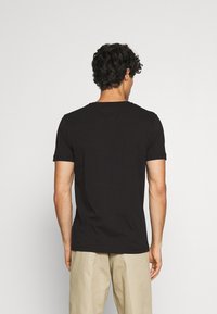 Camiseta negra de manga corta hecha de algodón, con un cuello redondo y un diseño simple, con un dobladillo recto y sin logotipos visibles.