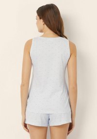 Conjunto de pijama azul claro que incluye una camiseta sin mangas con patrones de corazones rosas y pantalones cortos a juego, hecho de una tela suave y ligera.
