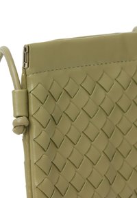 Olivezelená kožená kabelka cez telo s tkanou diamantovou textúrou, elegantným dizajnom a kovovým zipsom na vrchu.