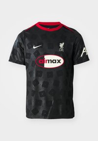 Camiseta de fútbol negra de manga corta, cuello redondo, con detalles en rojo, logo de L.F.C. y un patrón abstracto de cuadrados. Logo de Nike en el lado derecho del pecho.