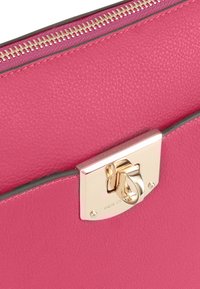 Roze leren clutch met een gestructureerde afwerking, voorzien van een gouden sluiting en rits. Gekenmerkt door een subtiele logo op de sluiting.