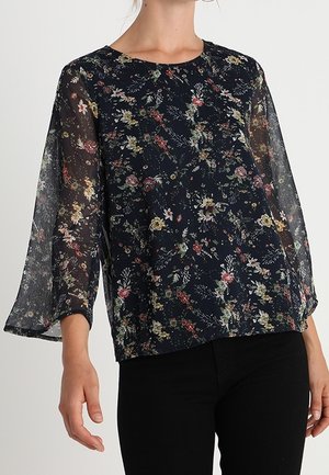 Top a fantasia floreale in blu navy, con lunghe maniche trasparenti e scollatura rotonda. Tessuto leggero con una vestibilità rilassata e una leggerissima texture.