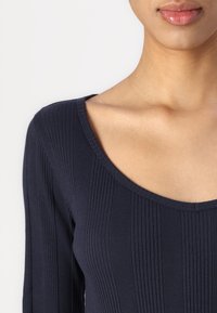 Laine longo navy com textura canelada e decote largo, apresentando uma textura suave e silhueta ajustada.