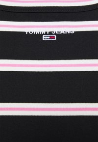 Czarny top w paski z poziomymi pasami w kolorze białym i różowym. Nazwa marki "TOMMY JEANS" jest wyszyta powyżej małego logo.