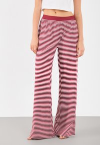 Red and white striped wide-leg pants with an elastic waistband and a relaxed fit. Soft fabric with vertical stripes.