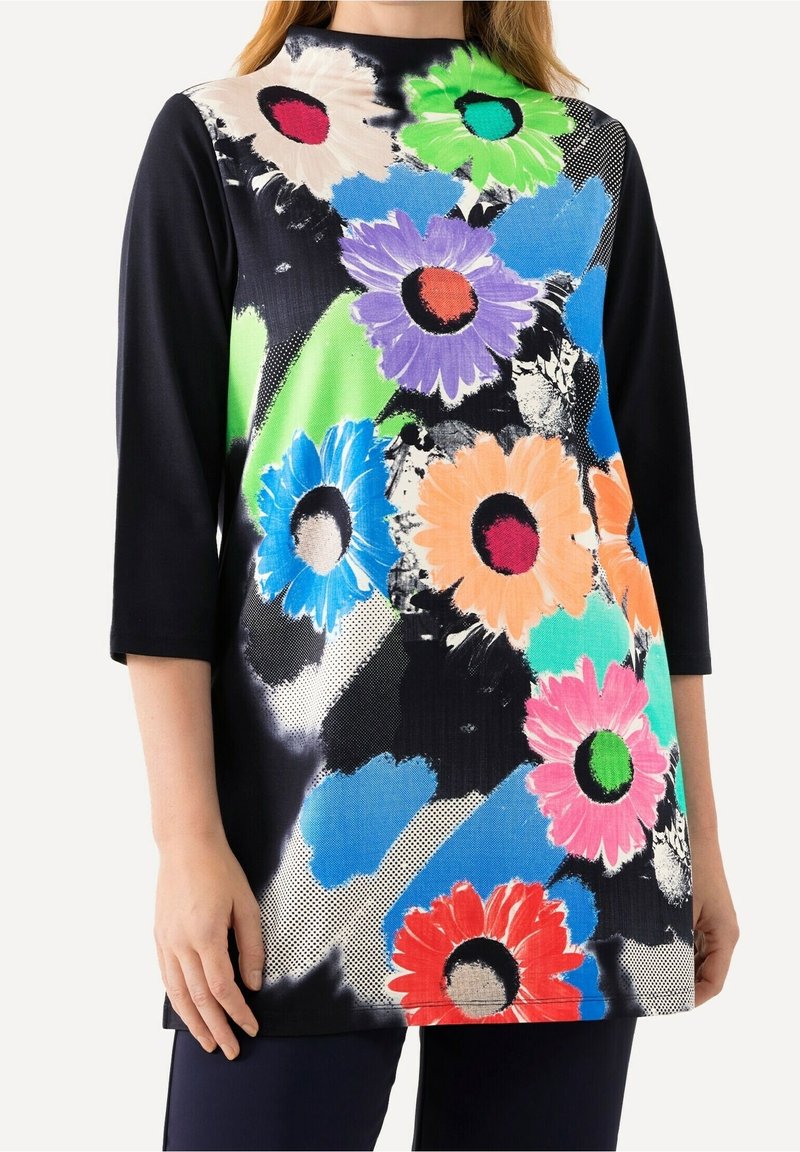 Langärmlige Tunika mit schwarzem Grund und mehrfarbigen Blumenmustern in Pink, Orange, Lila und Blau auf einem strukturierten Stoff.