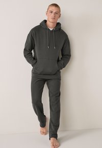 Dunkelgraues Hoodie- und Jogginganzug-Set aus weichem Stoff. Verfügt über eine Fronttasche, Kordelzüge und gerippte Bündchen an den Hosen.