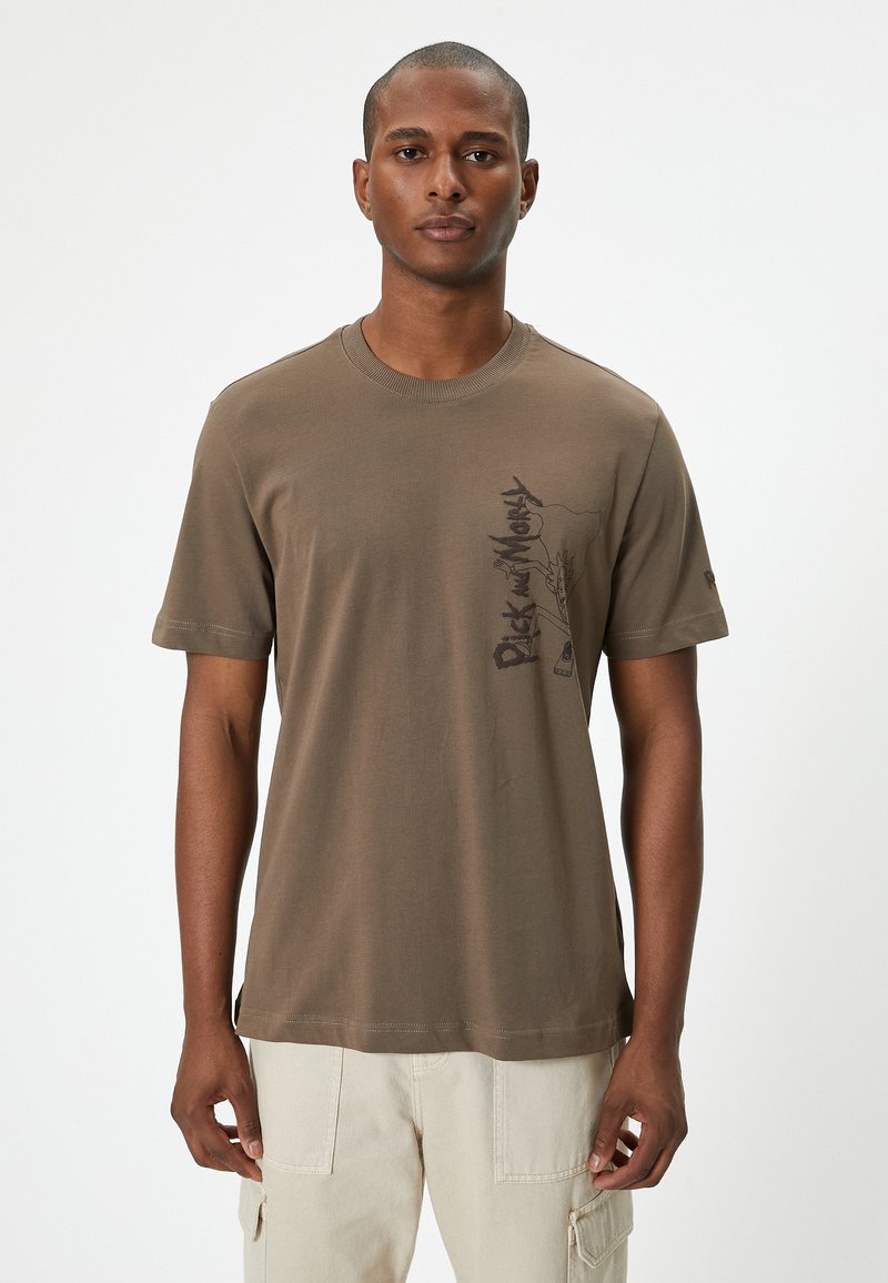 Olivenfarvet bomulds T-shirt med korte ærmer, rund halsudskæring og et grafisk print på venstre side, der viser tekst og abstrakt design.