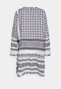 Tunique à motif gris et blanc, présentant un design pied-de-poule, coupe ample, manches trois-quarts et accents texturés à rayures.