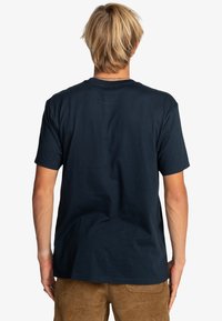 Námořnická modrá bavlněná tričko, krátké rukávy, kulatý výstřih, hladká textura, jednoduchý design, s volným střihem a bez viditelných log nebo grafik.