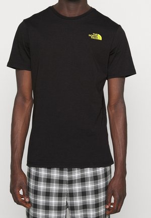 T-shirt en coton noir avec col rond et manches courtes, orné d'un petit logo jaune sur le côté gauche de la poitrine. Texture lisse, coupe ajustée.