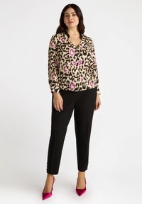Leopard print blouse in beige, black, and purple, with a V-neck and long sleeves, paired with black pants featuring gold button accents.