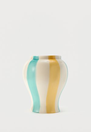 Vase en céramique à forme courbée présentant de larges rayures verticales en bleu sarcelle et jaune moutarde sur un fond crème.